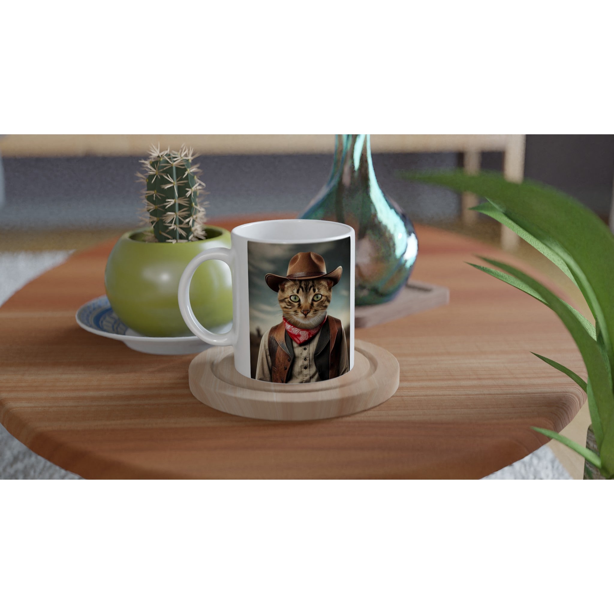 Mug blanc posé sur plateau en bois illustré d’un chat costumé en cow-boy (chapeau, bandana rouge, gilet), sur une table en bois avec un cactus en pot et une plante verte.