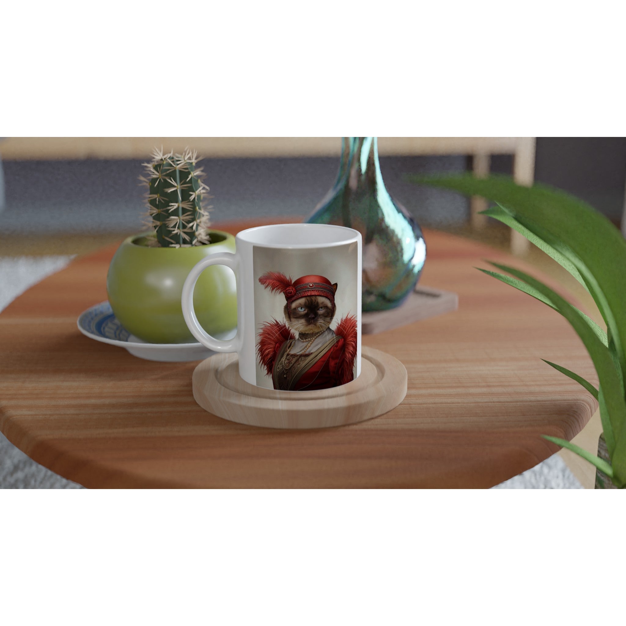 Mug blanc posé sur une table en bois, orné d’un portrait de chat en costume rouge style années 1920 (plumes et perles), à côté d’un cactus en pot vert et d’un vase décoratif.