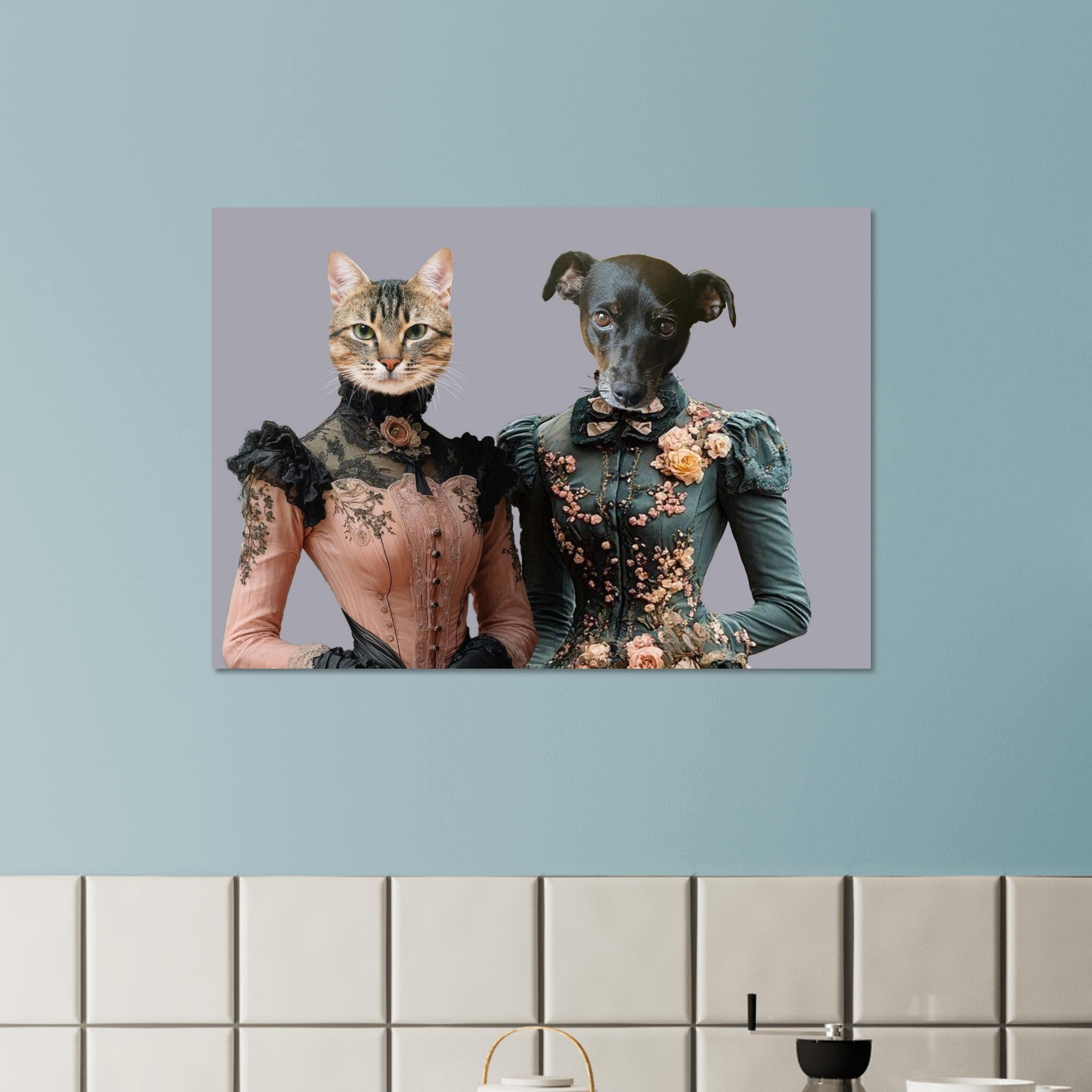 Tableau mural représentant un chat et un chien anthropomorphes en robes victoriennes richement décorées, accroché sur un mur bleu au-dessus d’un plan de travail carrelé.