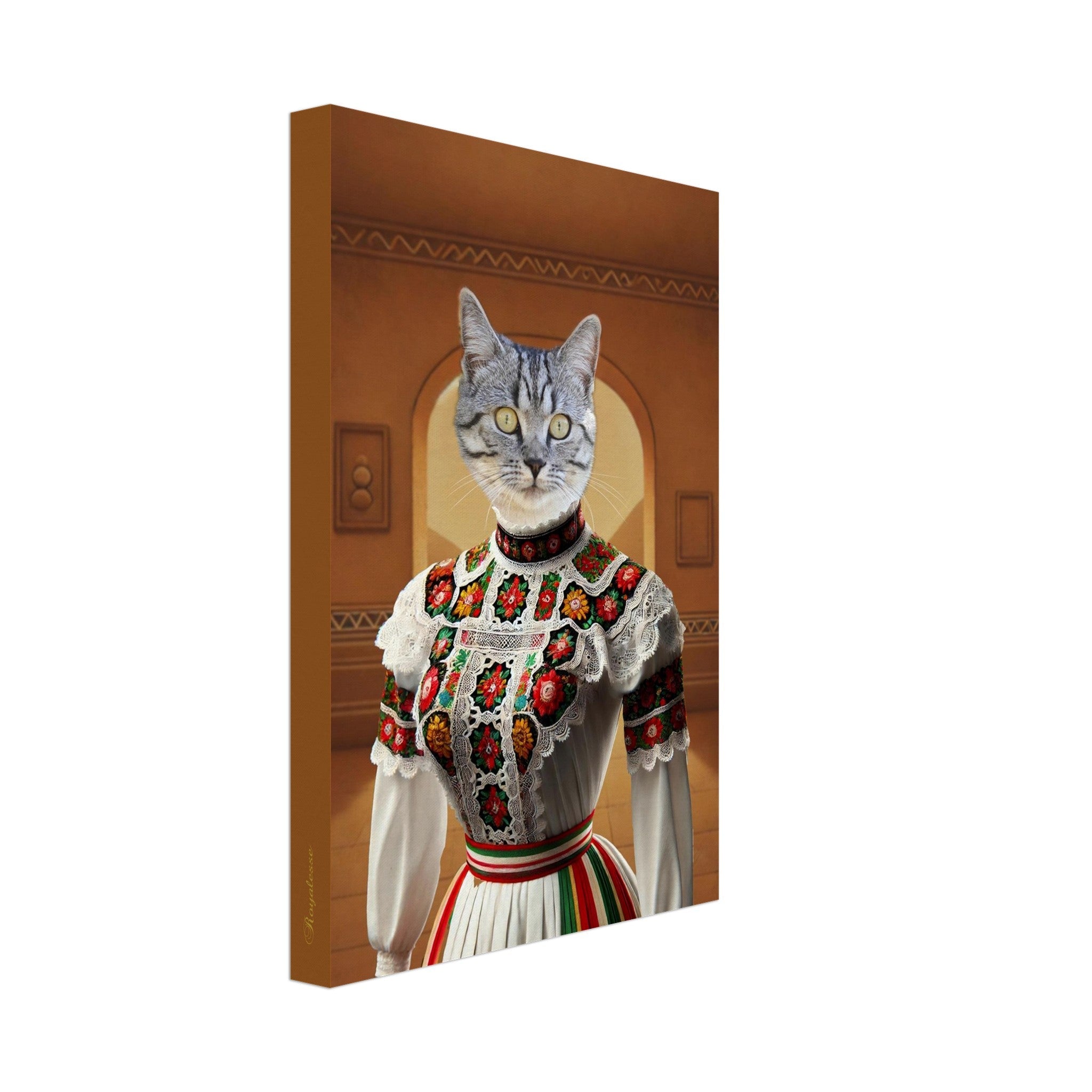 Portrait sur toile d’un chat tigré gris à yeux jaunes vêtu d’une robe folklorique blanche richement brodée de fleurs colorées et de dentelle, sur fond d’intérieur aux tons chauds.