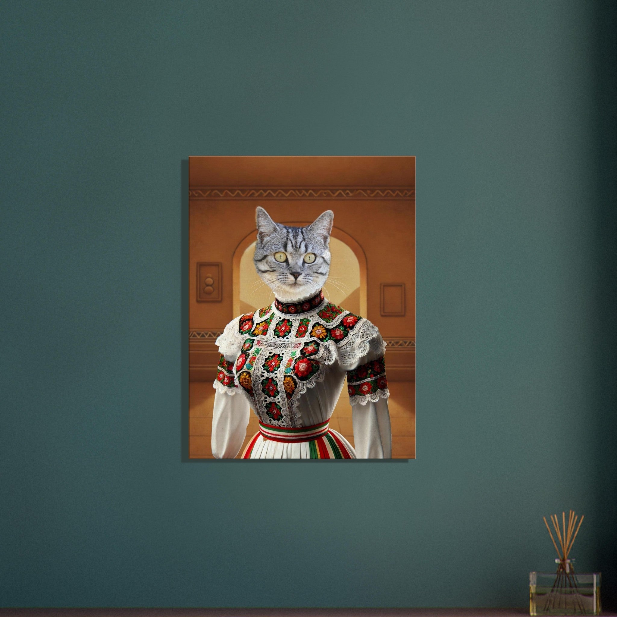 Portrait d’un chat tigré aux yeux jaunes fusionné à un buste féminin vêtu d’une robe folklorique blanche richement brodée de motifs floraux rouges, verts et jaunes et rehaussée de dentelle, sur un fond d’intérieur ocre.