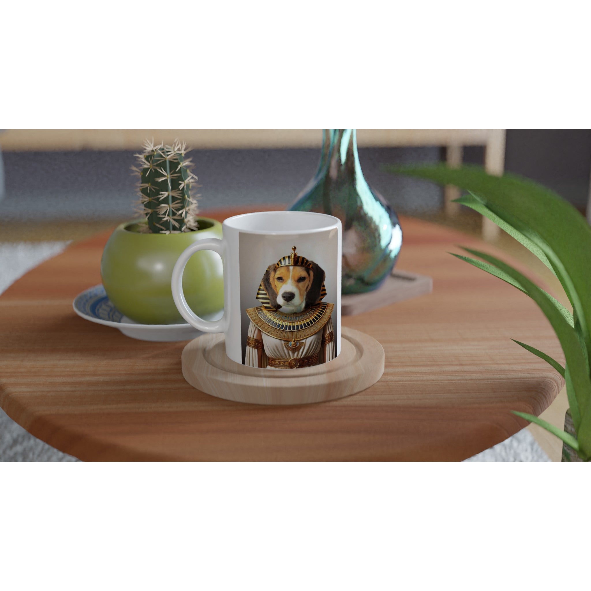 Tasse blanche posée sur une table en bois, ornée d’un portrait de chien en costume de pharaon égyptien, à côté d’un petit cactus en pot vert et d’un vase irisé.