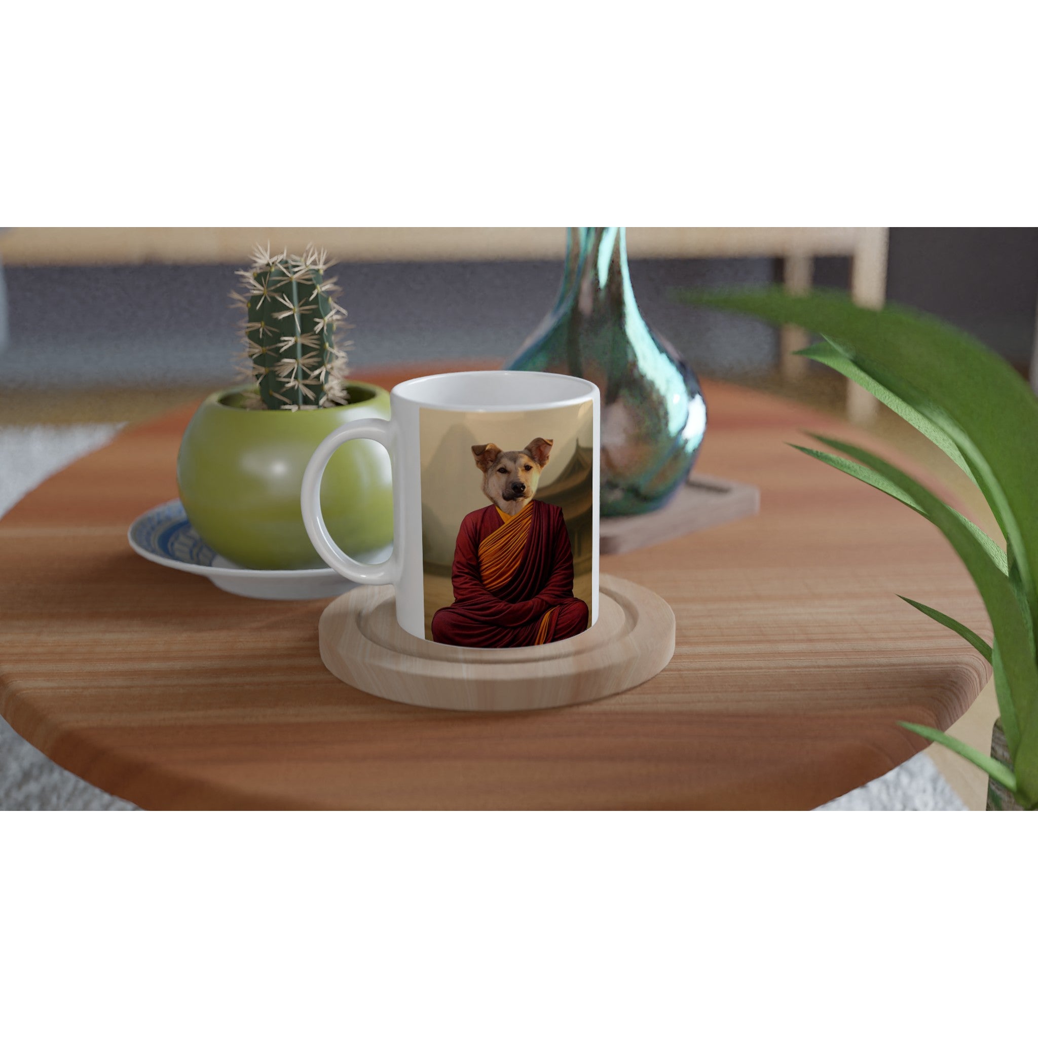 Mug blanc posé sur une table en bois avec l’image d’un chien méditant en robe bouddhiste rouge et jaune, accompagné en arrière-plan d’un cactus en pot vert et d’un vase turquoise.