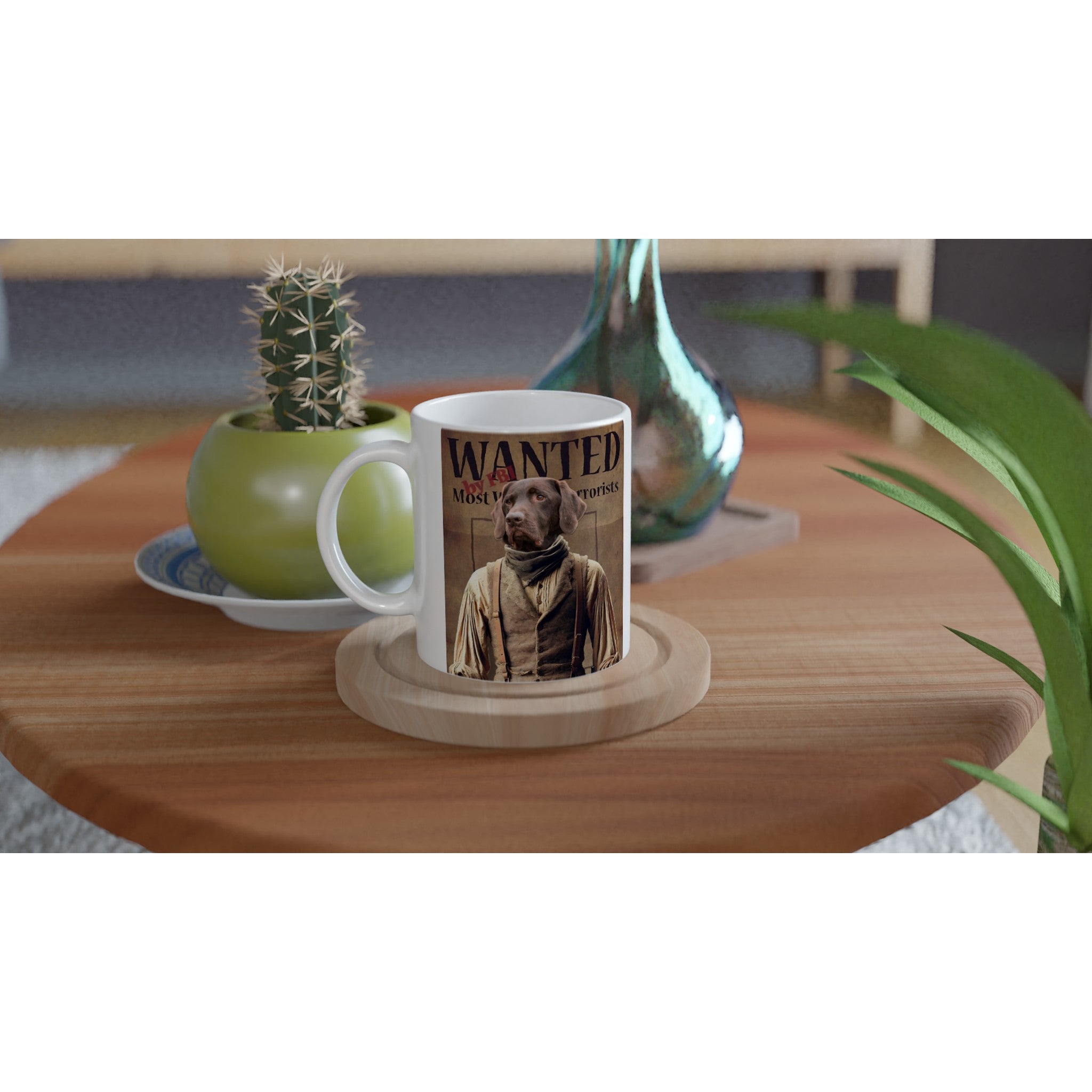 Tasse blanche posée sur un sous-verre en bois sur une table basse, ornée d’une affiche « Wanted » style western avec un chien en costume d’époque, à côté d’un petit cactus en pot vert et d’un vase décoratif irisé.