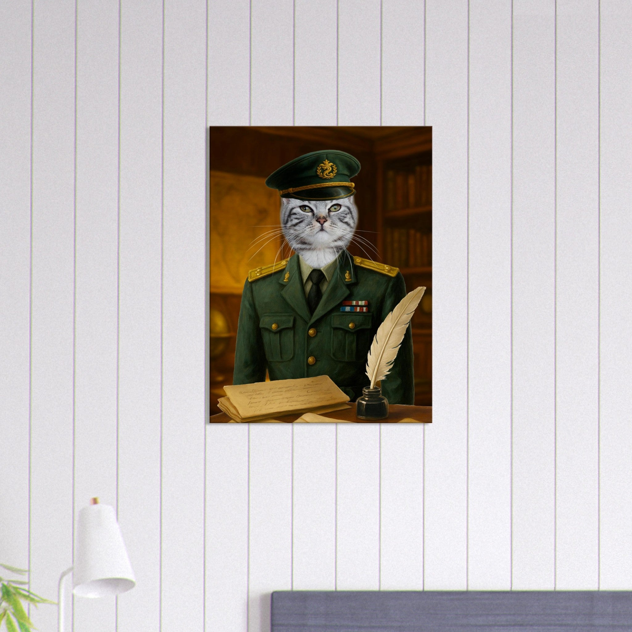 Chat tigré gris portant un uniforme militaire vert à galons et un képi, posé derrière un bureau en bois avec une plume, un encrier et des parchemins, devant une bibliothèque ancienne.