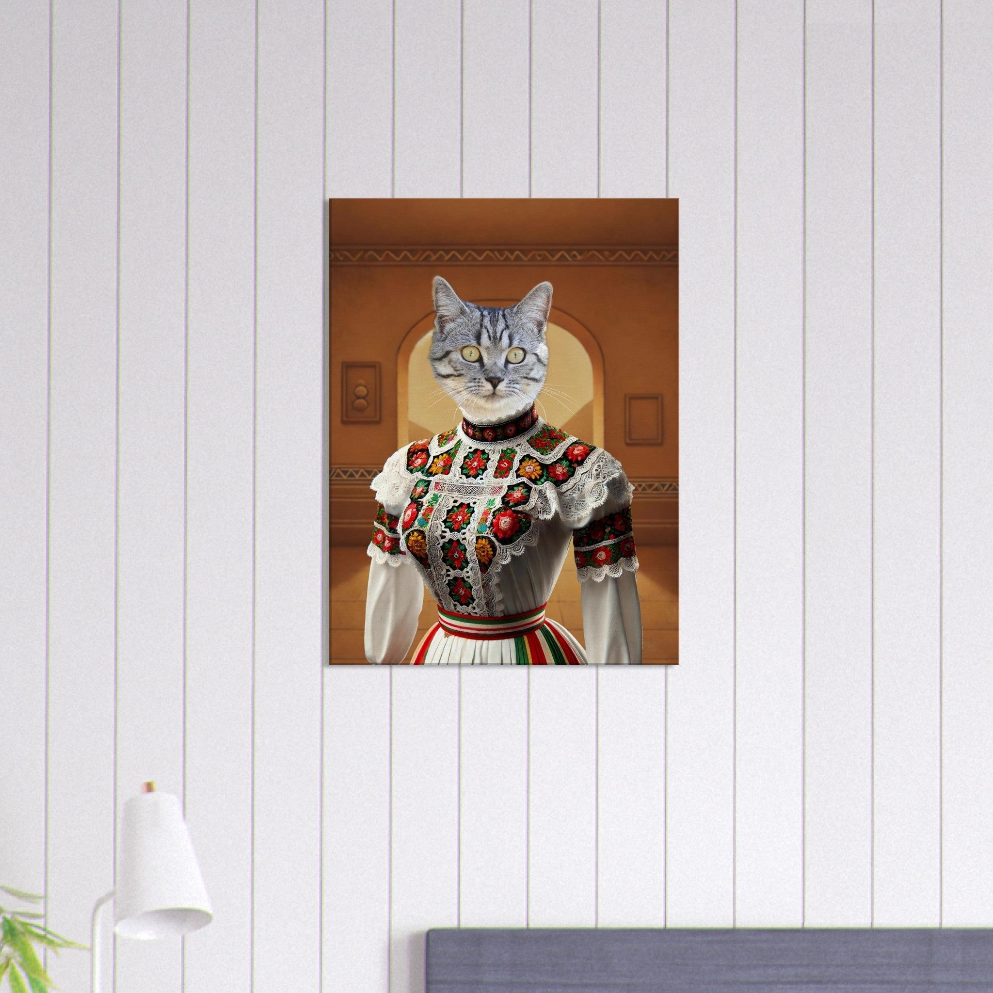 Portrait stylisé d’un chat gris au regard perçant, vêtu d’une robe folklorique blanche richement brodée de motifs floraux rouges, verts et jaunes, sur fond d’arcade ocre.