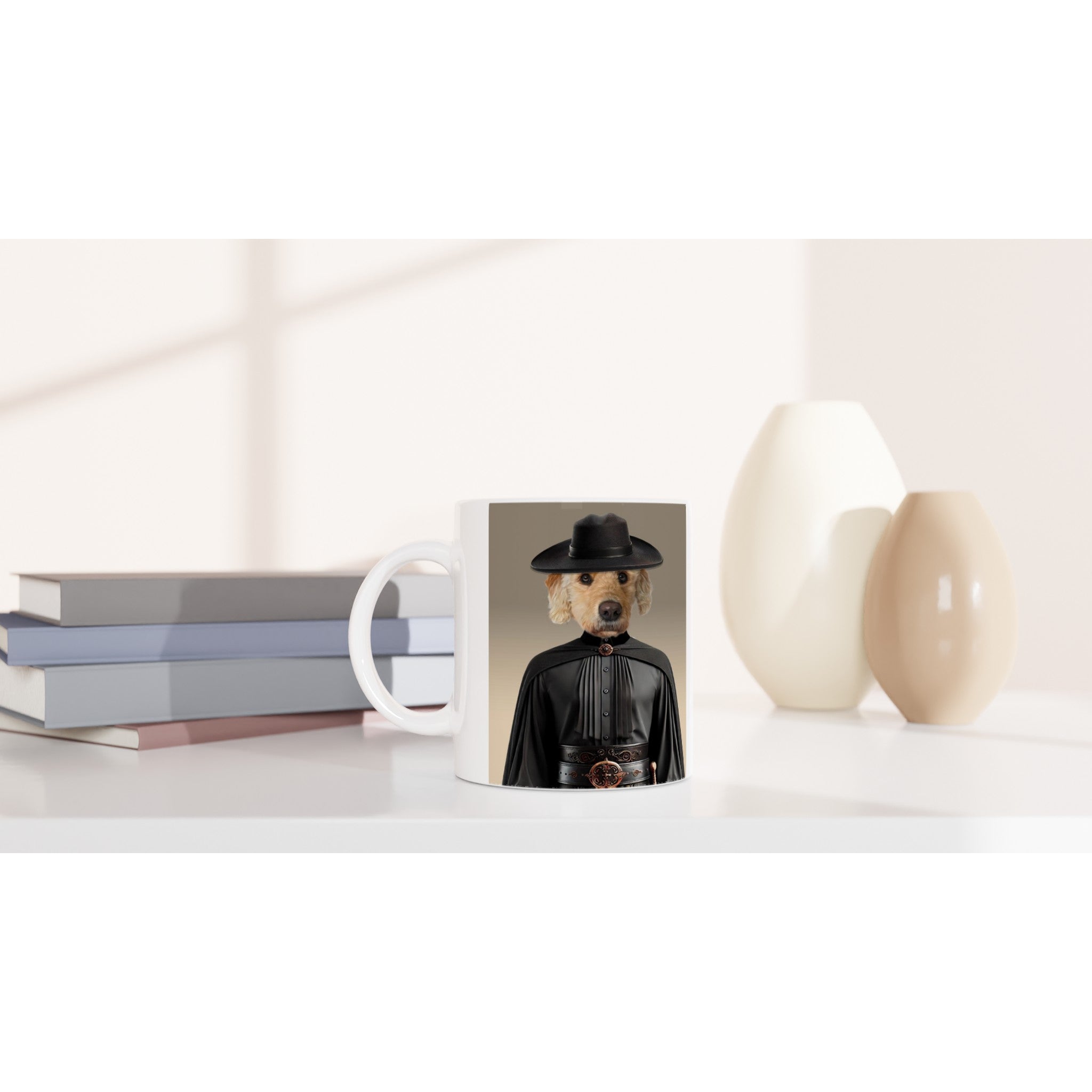 Mug blanc sur une étagère minimaliste, imprimé d’un chien portant un chapeau noir et une cape façon Zorro, à côté de livres pastel et de deux vases crème.