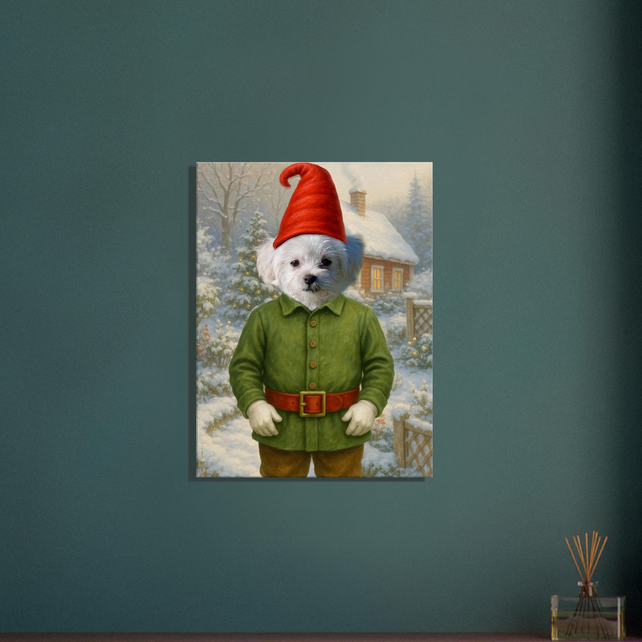 Petit chien blanc habillé en lutin de Noël (veste verte, ceinture rouge, chapeau pointu) debout devant un chalet enneigé.