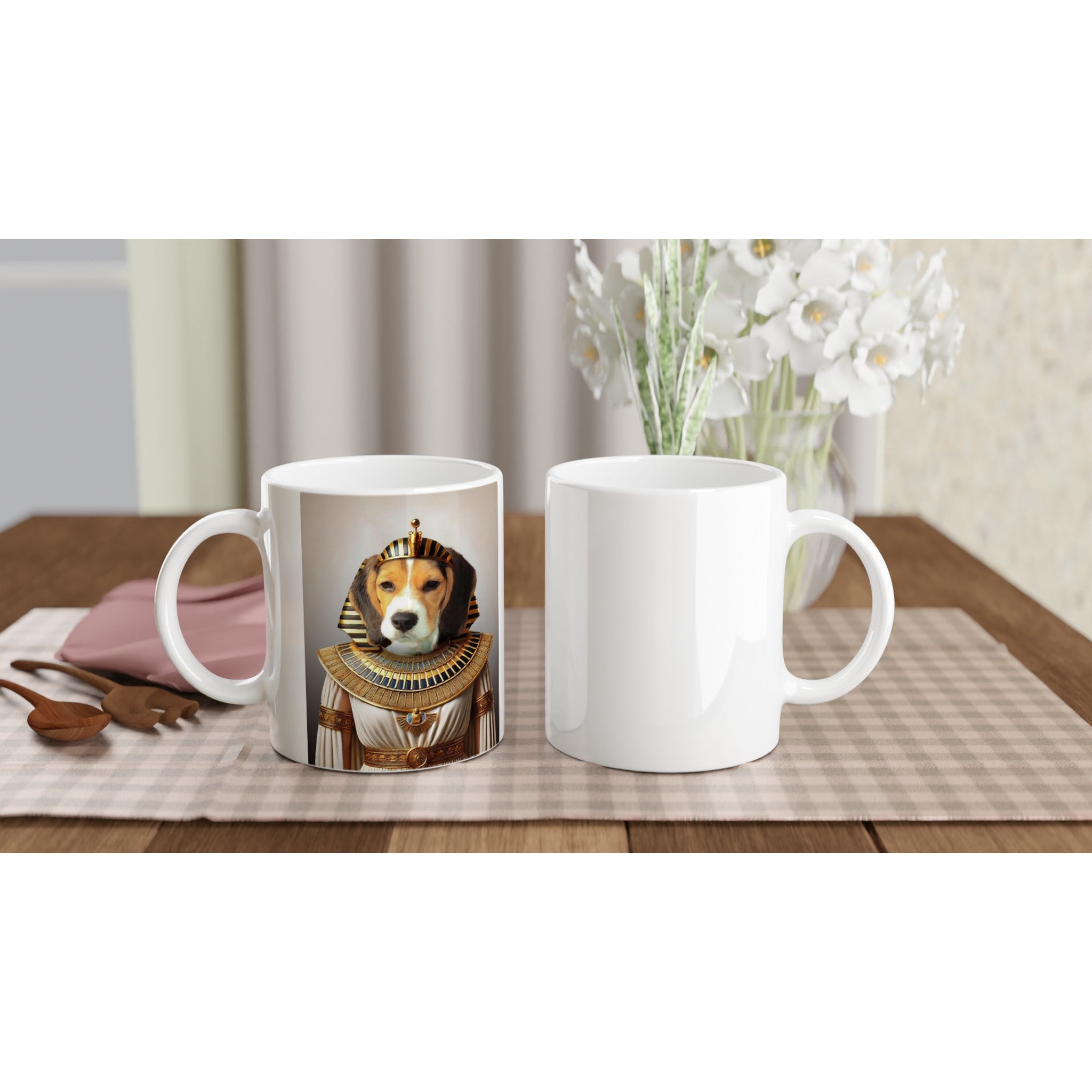 Photo d’un mug blanc personnalisé imprimé d’un beagle en costume de pharaon égyptien, posé à côté d’un mug blanc vide sur une table en bois avec un napperon à carreaux et un vase de fleurs blanches.