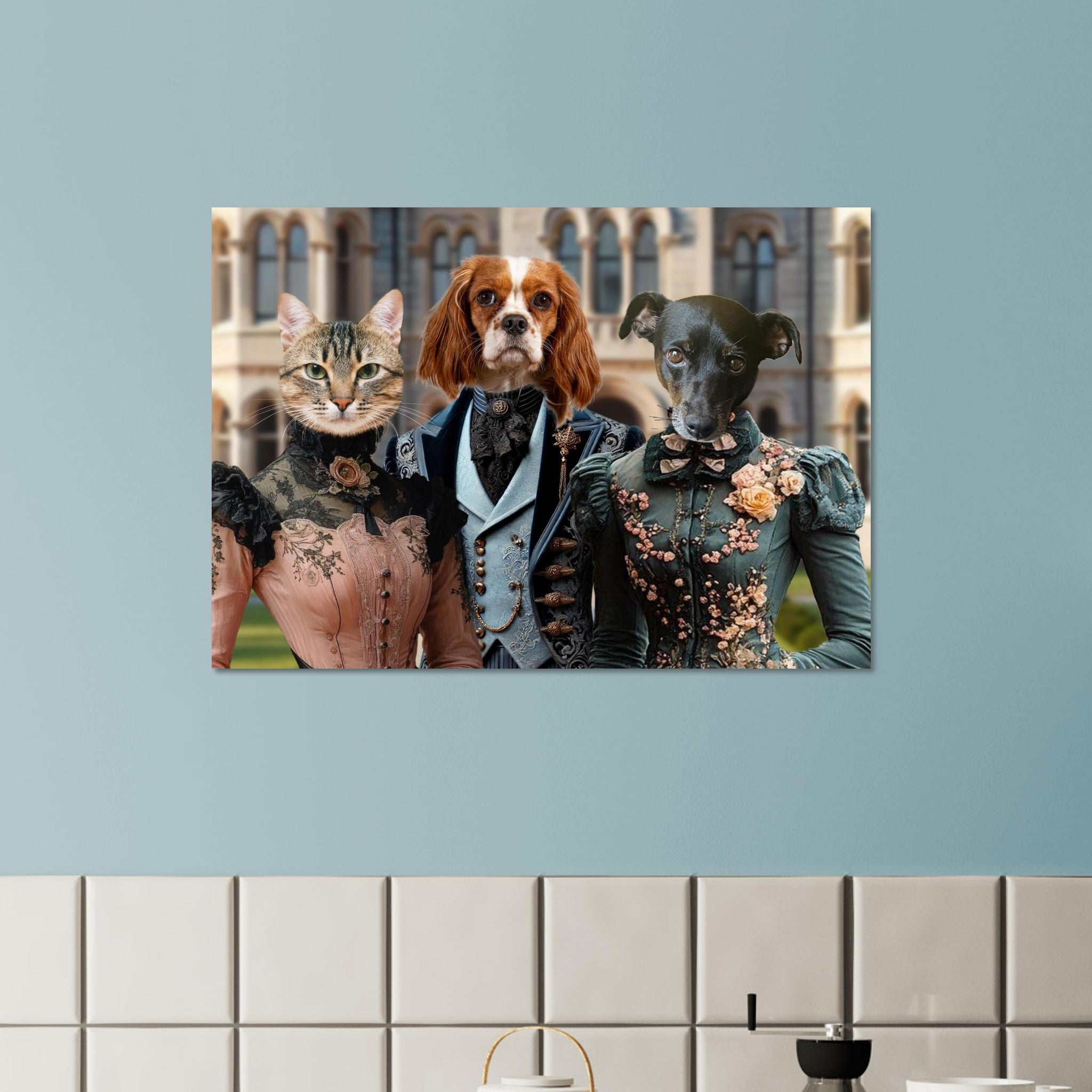 Portrait mural de trois animaux costumés en aristocrates victoriens : un chat en robe rose à dentelle, un épagneul cavalier en redingote bleue et un petit chien noir en robe verte brodée, suspendu sur un mur bleu au-dessus d’une crédence de carrelage blanc.