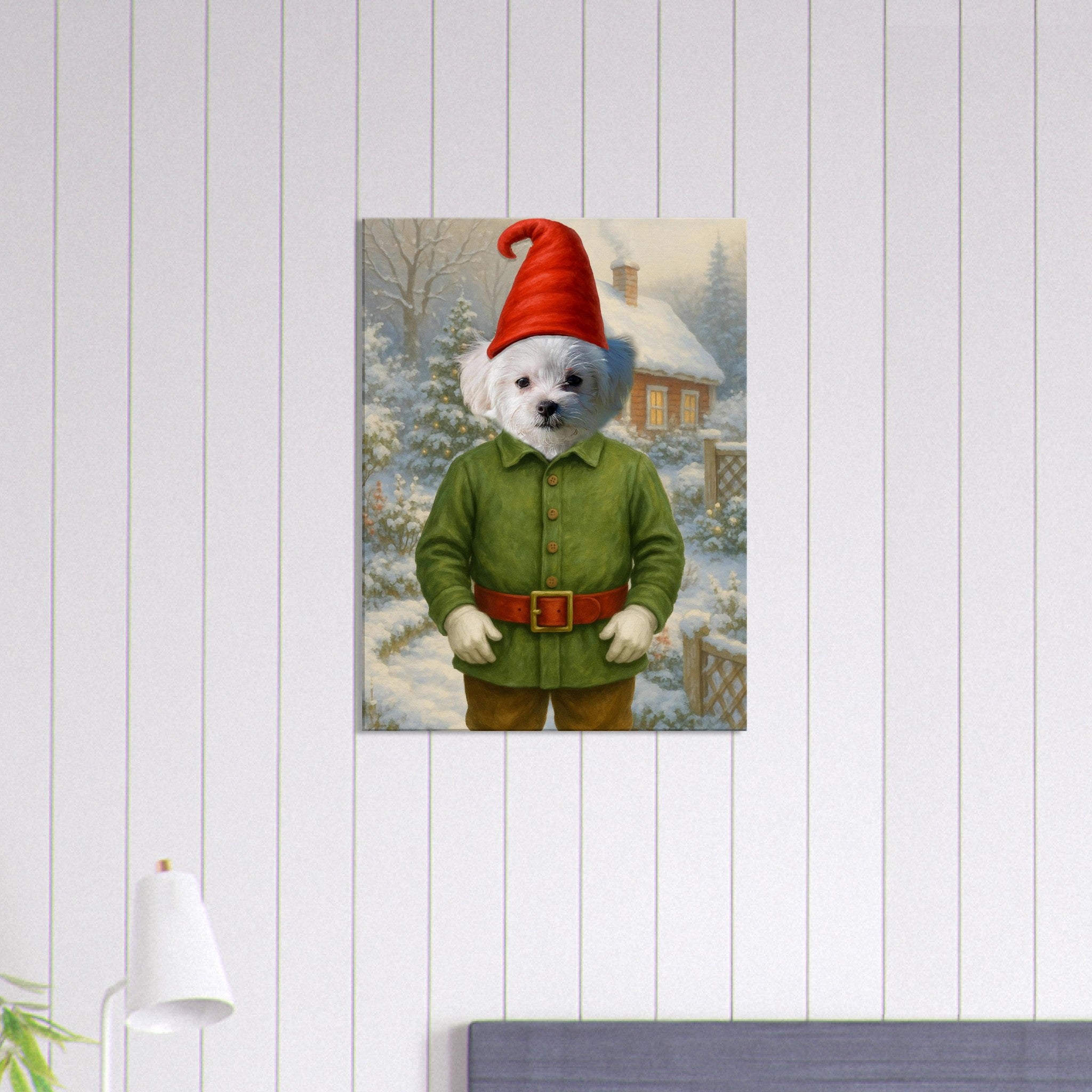 Petit chien blanc debout en costume de lutin de Noël (tunique verte, ceinture rouge, bonnet pointu) devant un chalet enneigé et un paysage forestier hivernal.
