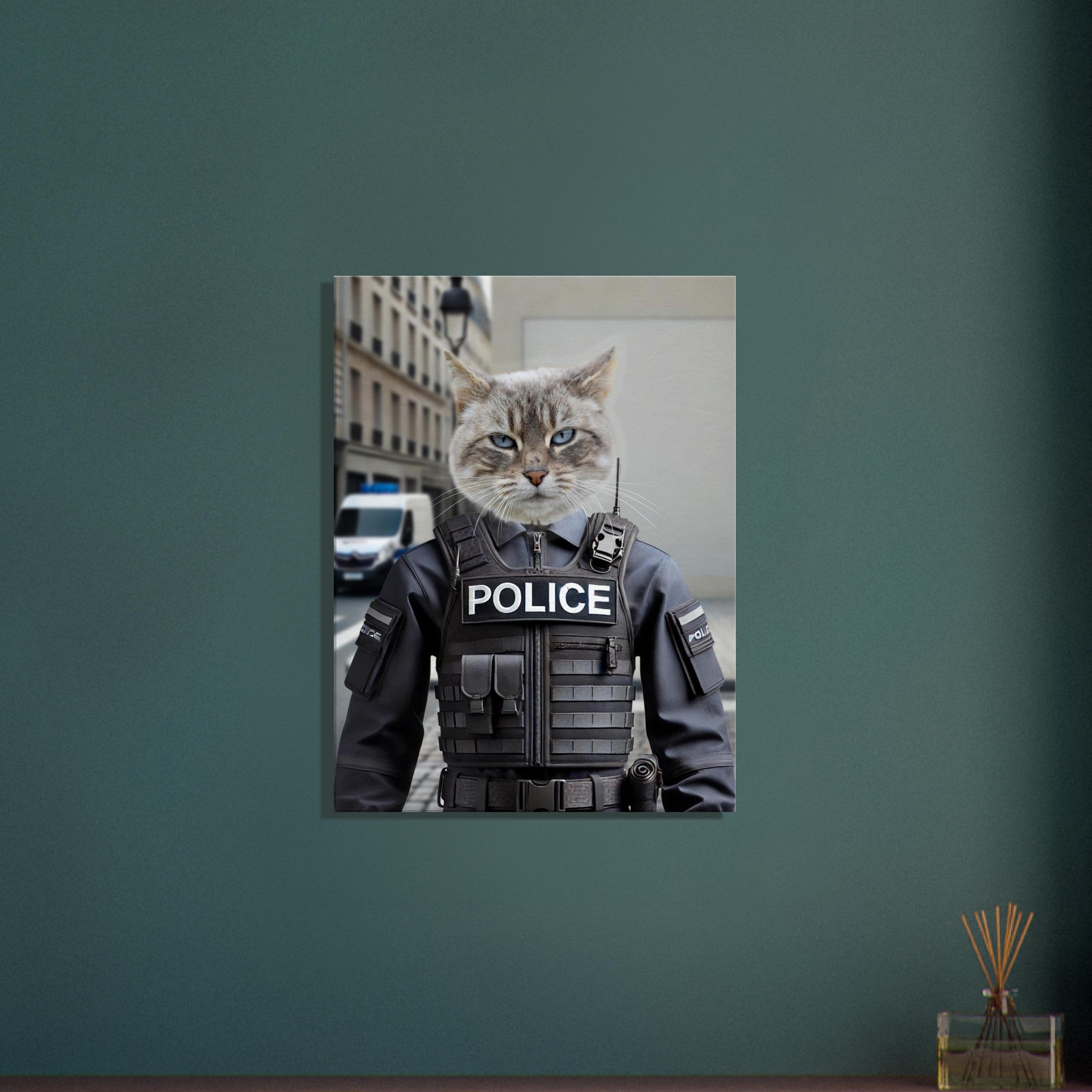 Portrait d’un chat gris aux yeux bleus vêtu d’un gilet tactique noir marqué « POLICE », debout dans une rue urbaine avec un immeuble et un véhicule de police en arrière-plan.